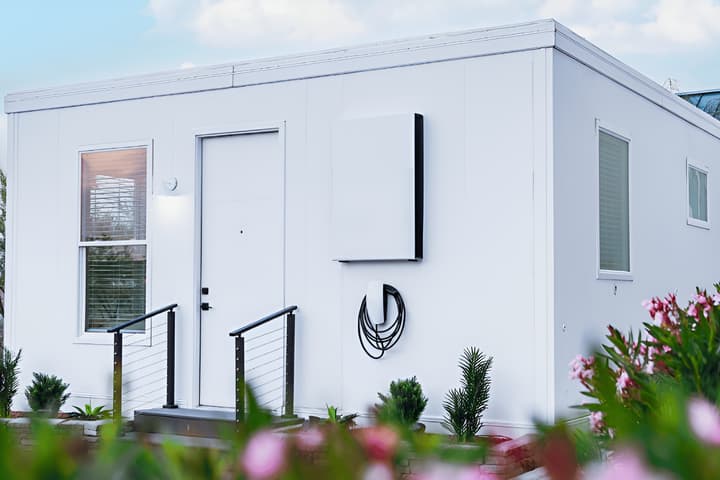 The exterior of the Boxabl Casita tiny home, shown with a Tesla charger mounted to the outside