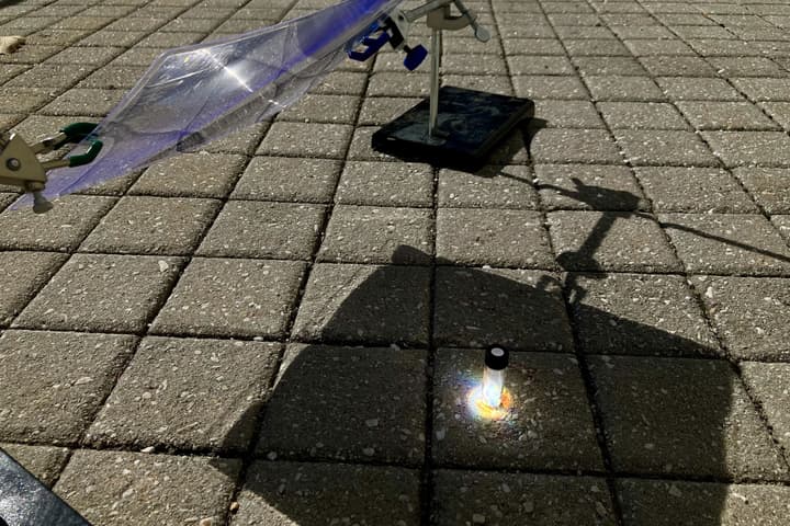 Sunlight is focused onto a vial containing a piece of post-consumer black polystyrene