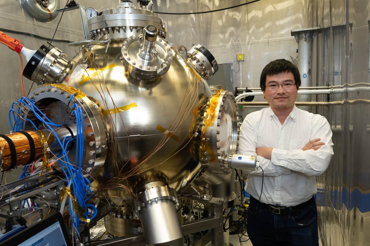 Physicist Erdong Wang poses next to the high-voltage electron gun he conceived of in 2017