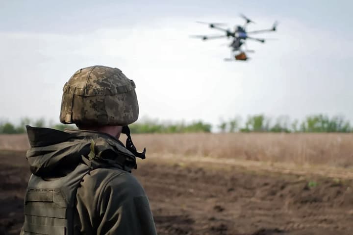 A soldier looks on as a drone flies nearby